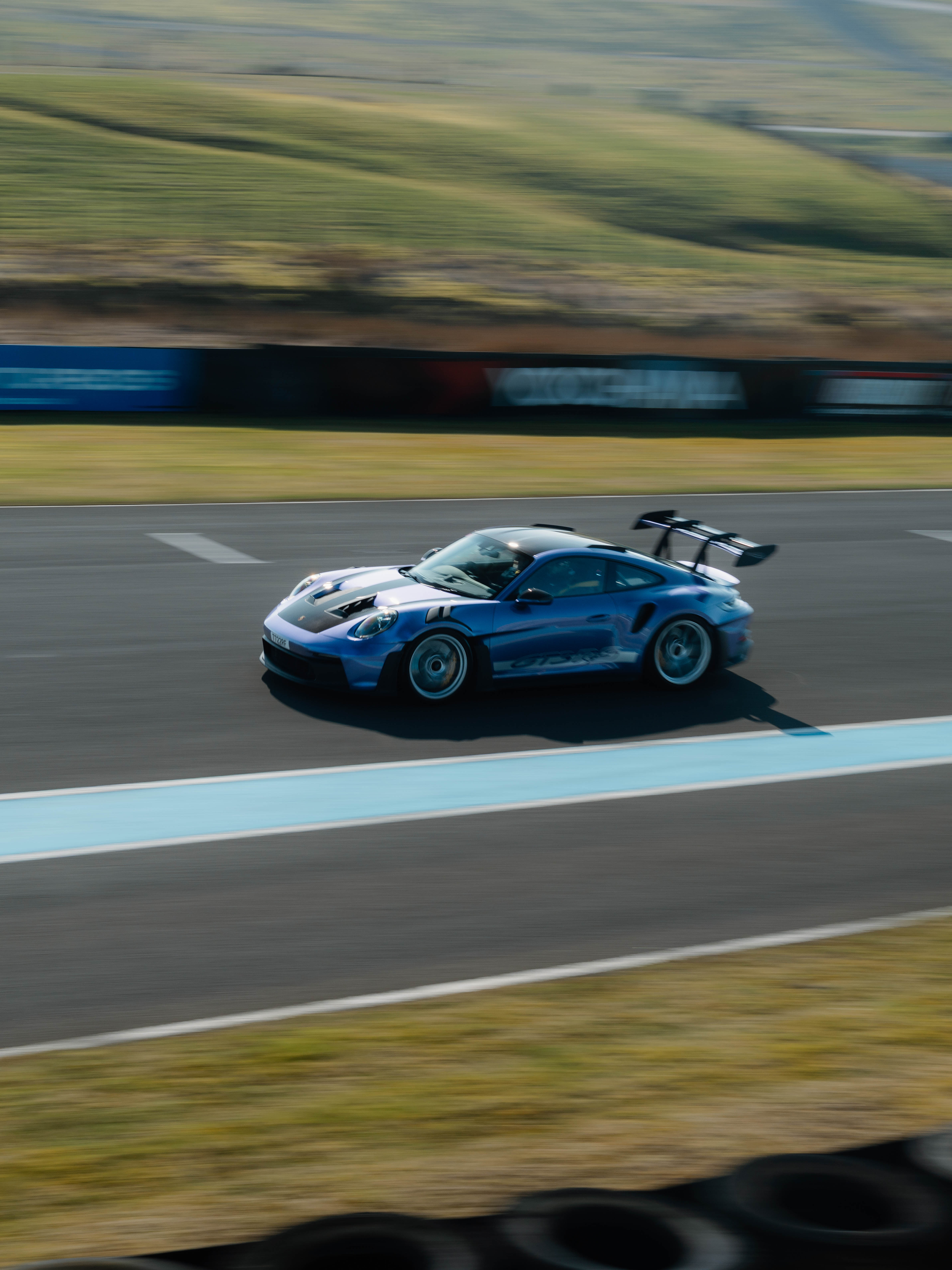 A blue Porsche drives down a race track at great speed